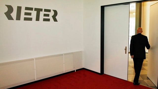 Verwaltungsratspräsident Erwin Stoller beim Verlassen eines Zimmers mit dem Rieter-Logo an der Wand.