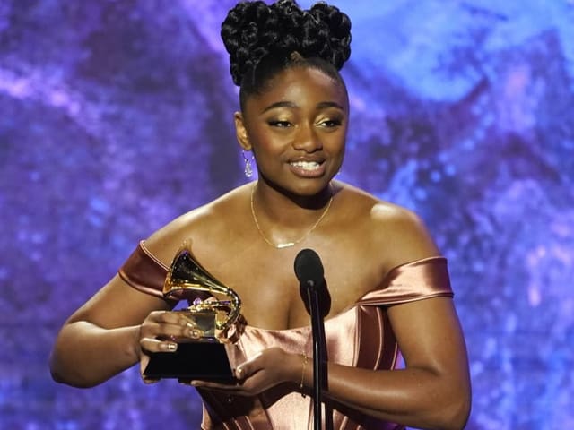 Samara Joy hält den Grammy in der Hand und spricht ins Mikrofon.