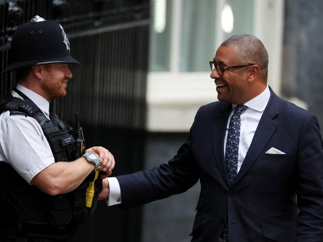 James Cleverly spricht mit einem Polizisten, beide lachen