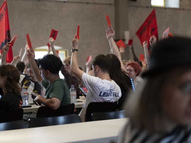 Menschen heben rote Karten bei einer Versammlung.