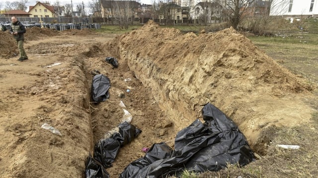 Blick in ein Massengrab, mehrere Leichen befinden sich in schwarzen Plastiksäcken