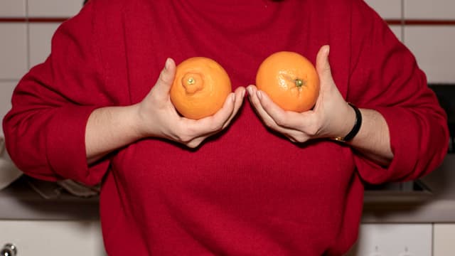 Eine Frau hält zwei Orangen in den Händen.