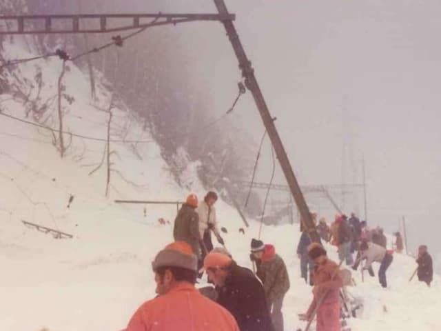 Foto von 1975: Menschen schaufeln ein Bahngleis frei, dass von einer Lawine verschüttet wurde.