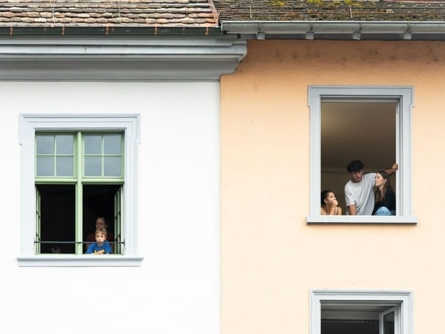 Bewohner:innen gucken aus ihren Fenstern