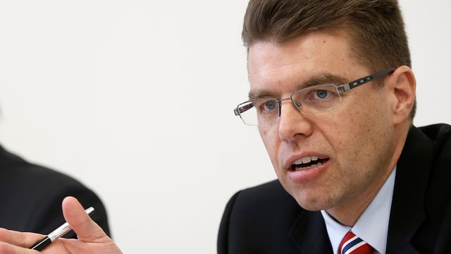 Andreas Rickenbacher bei einer Medienkonferenz, ein Stift in der Hand.