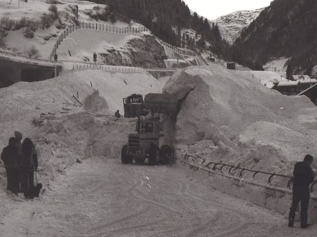 Schwarz-weiss Foto: Bagger an der Arbeit die Lawine wegzuräumen.