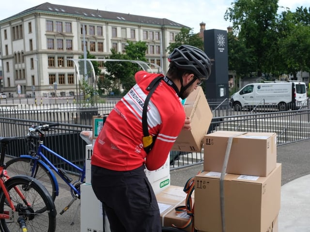 Ein Velokurier lädt ein Paket vom Velo. 