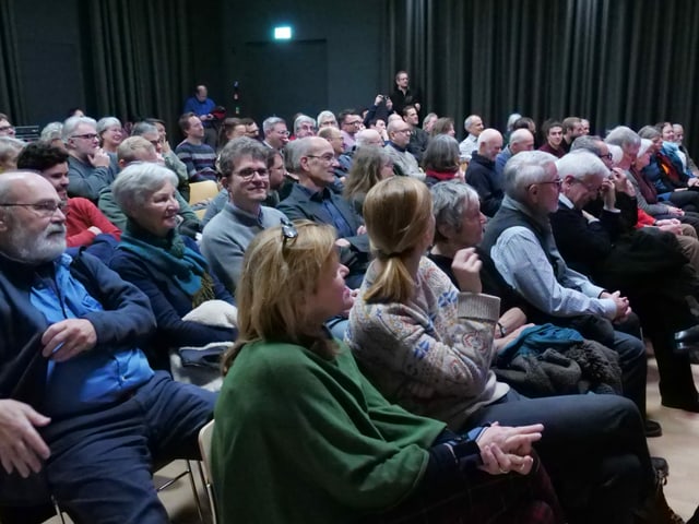 Viele Leuten sitzen auf Stühlen.