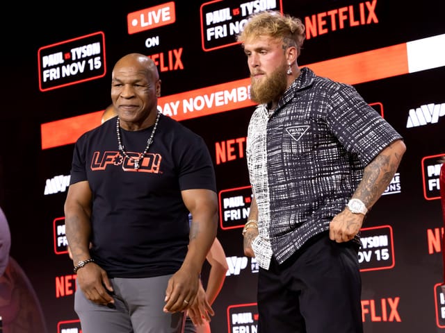 Mike Tyson und Jake Paul stehen auf einer Bühne vor Netflix-Werbung.