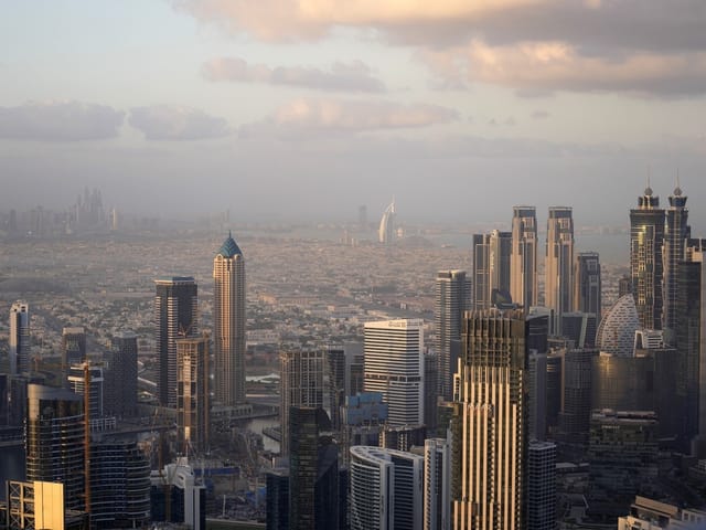 Luftaufnahme einer modernen Stadt mit Hochhäusern bei bewölktem Himmel.