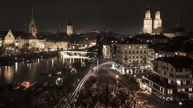 Blick auf die Zürcher Altstadt bei Nacht mit zahlreichen hell erleuchteten Kirchtürmen.