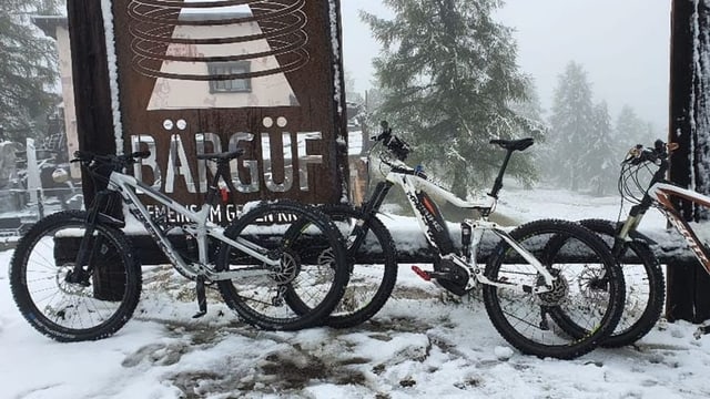 Fahrräder stehen im Neuschnee.