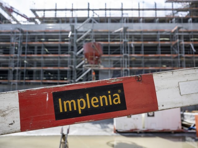 Implenia-Schild vor einem Baugerüst.