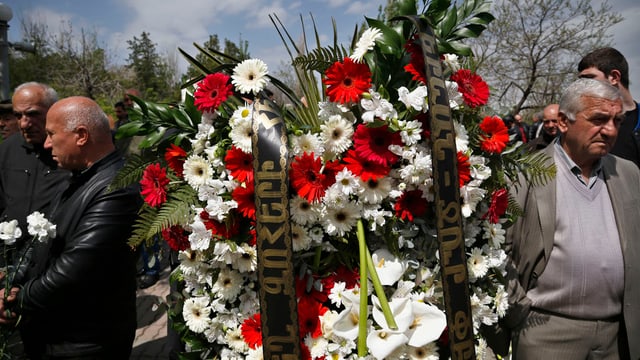 Menschen tragen einen Kranz aus Blumen. 