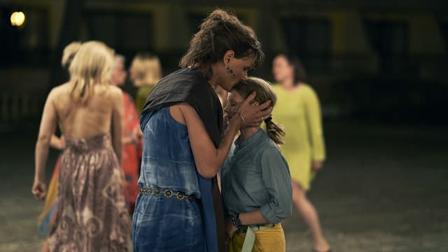 Movie scene: a woman kisses a girl on the forehead on the dance floor.