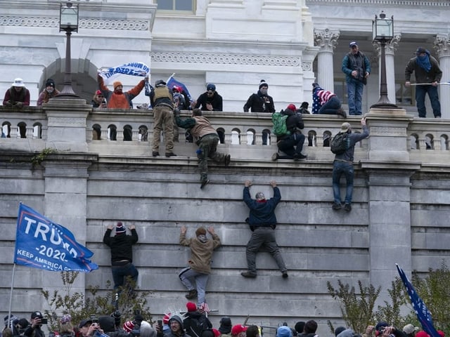 Menschen klettern über eine Mauer