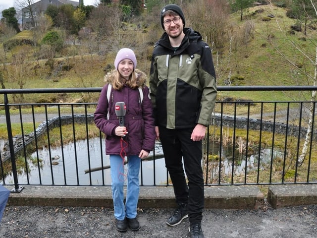 Ein Mädchen und ein Mann stehen vor einem Weiher