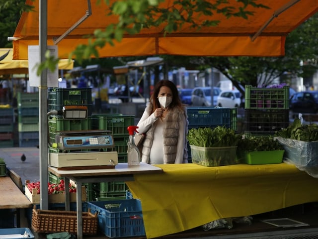 Woman wearing a mask at a market stall.