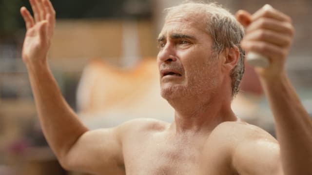 Ein verzweifelter, nackter Mann (Joaquin Phoenix als Beau Wassermann) hält seine Hände in die Höhe..