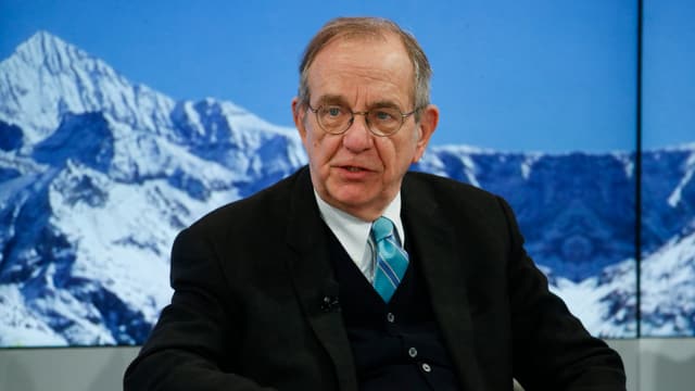 Padoan mit Brille sitzt an vor einem Wandbild mit Schneeberg.