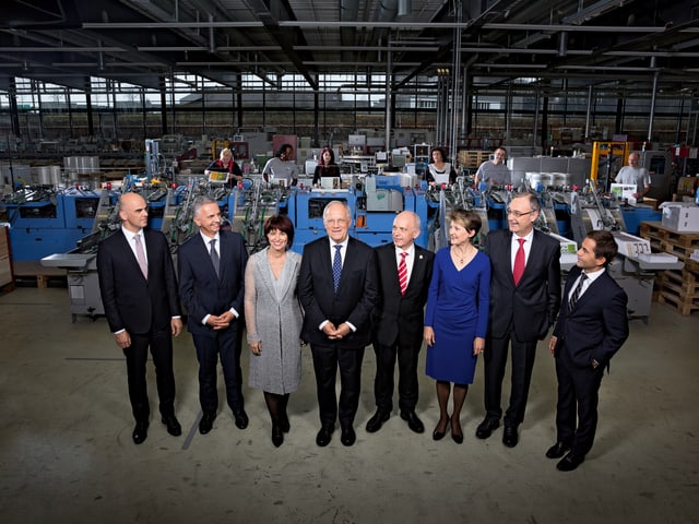 Members of the Federal Council are standing in a factory.