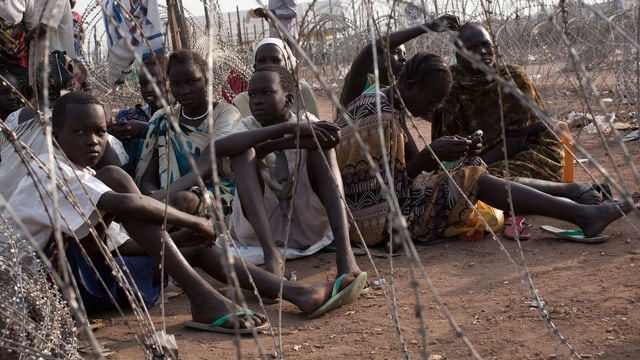 Flüchtlinge von der ethischen Gruppe der Nuer warten in einem Lager auf Essen.