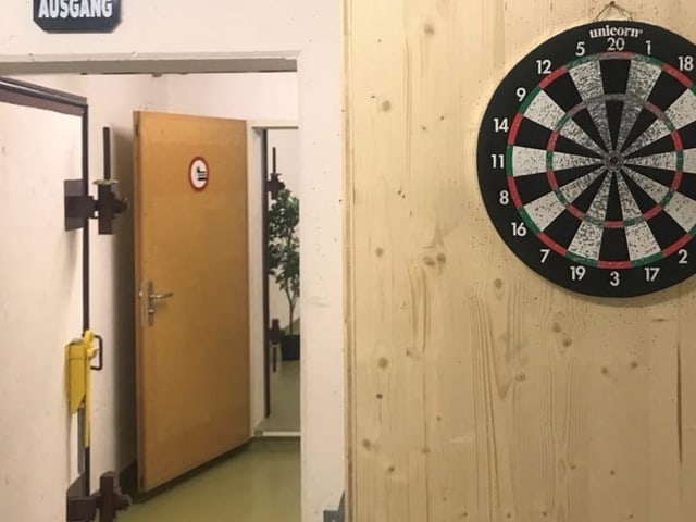 Dartscheibe auf Holzwand montiert, daneben Luftschutztüren im Bunkerstyle