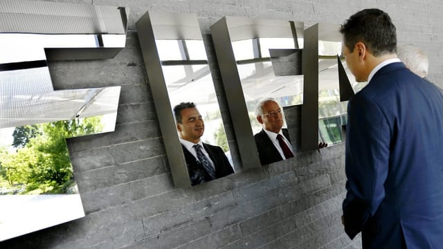 Garcia und Eckert vor dem FIFA-Logo, im welchem sich ihre Gesichter spiegeln.