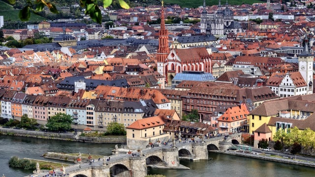 Eine Altstadt mit mehreren Kirchtürmen an einem Fluss. 