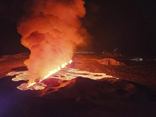 Ein langer Riss aus dem Lava aufsteigt. Darüber bilden sich orange-leuchtende Rauchschwaden.