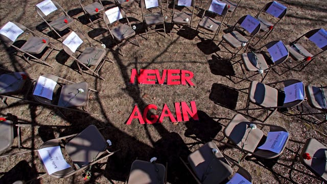 Ein Plenum mit leeren Stühlen und der Aufschrift "Never Again".