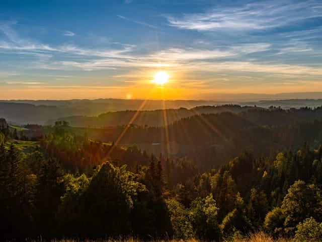 Sonnenaufgang über Wäldern und Hügeln