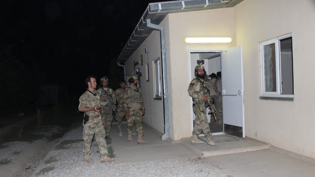 Soldaten stehen in der Nacht vor einem Haus 