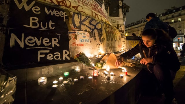 Eine Frau zündet im Gedenken an die Opfer der Anschläge von Paris eine Kerze an.