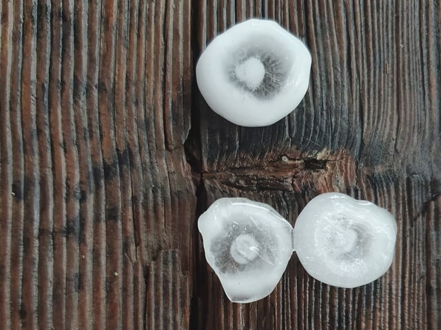 Drei Hagelkörner auf Holz mit Ringstrukturen