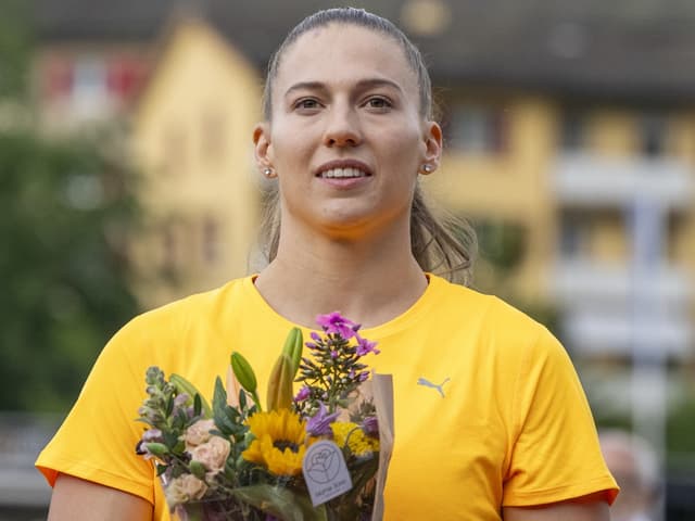 Porträt einer Frau in gelbem Hemd mit Blumenstrauss.