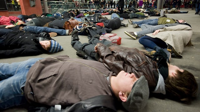 Ein Flashmob im Hauptbahnhof Bern: 50 Personen liegen auf dem Boden.