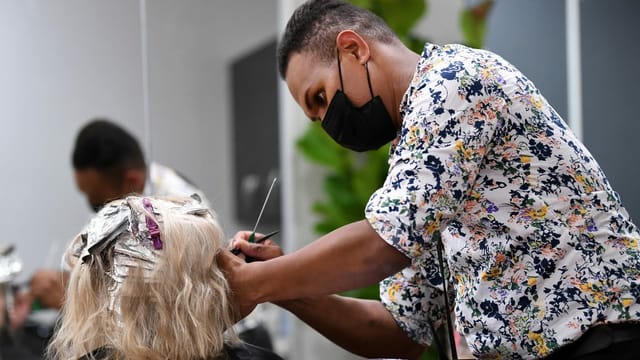 Coiffeur mit Schutzmaske und Kundin