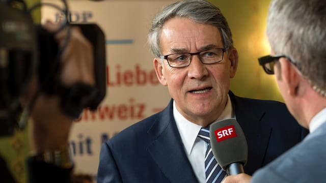 Urs Schwaller spricht in ein Mikrofon und wird dabei gefilmt.