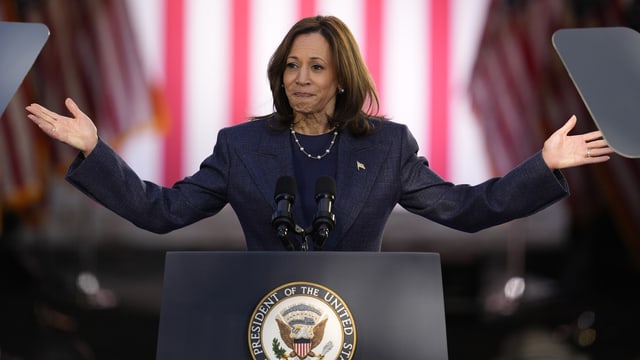 US-Präsidentschaftskandidatin Kamala Harris steht an einem Rednerpult und breitet die Arme aus.