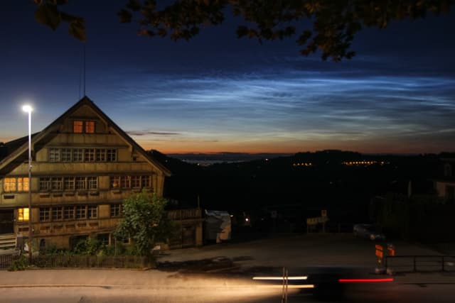 Silbern leuchtende Nachtwolken am dunklen Himmel.