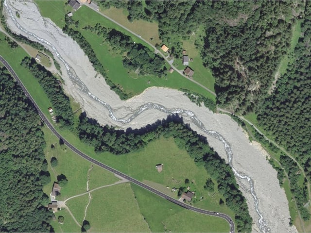 Luftbild eines mäandernden Flusses in einer grünen Landschaft mit Strassen und Gebäuden.