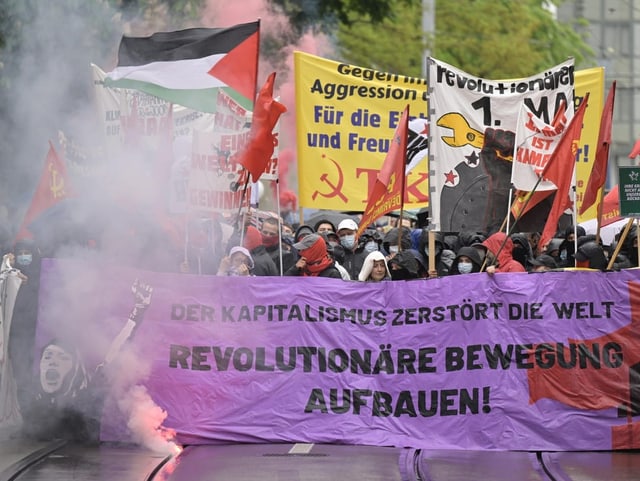 Blick auf die Spitze des Demonstrationszuges mit Bannern und Rauchfackeln.