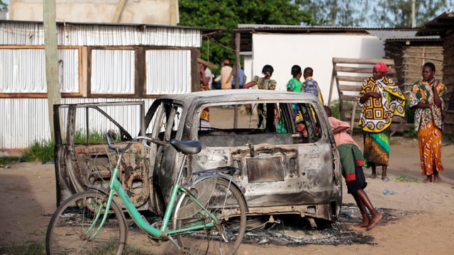 Ausgebranntes Auto auf einem afrikanischen Dorfplatz.