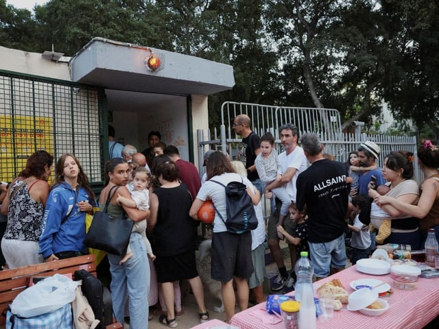 Gruppe von Menschen wartet in einer Warteschlange im Freien.