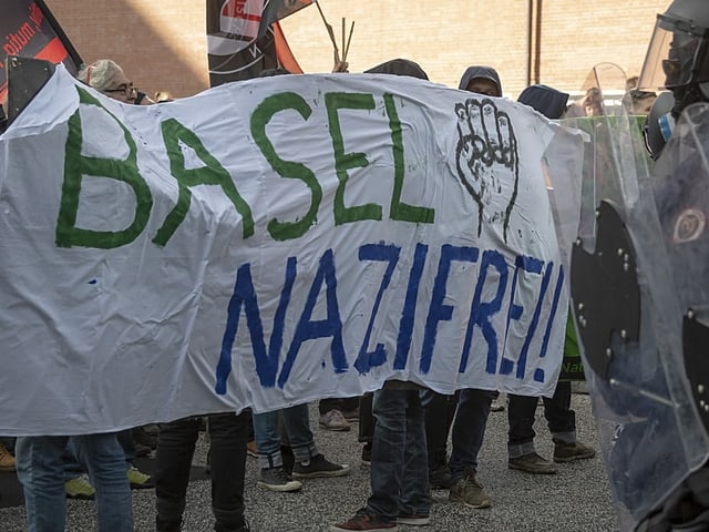 Demonstranten mit Banner vor Polizisten 