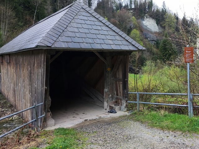 Holzbrücke mit Schild mit Informationen.