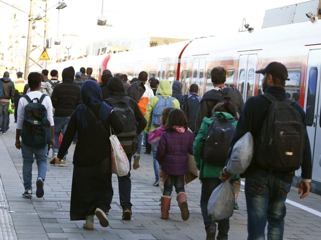 Flüchtlinge bewegen sich nach ihrer Ankunft in Richtung Haupthalle des Bahnhofs. 