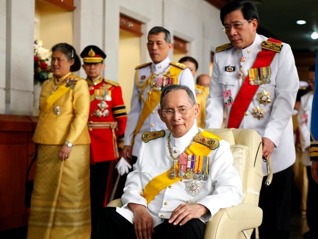 König Bhumibol sitzt in einem Rollstuhl.