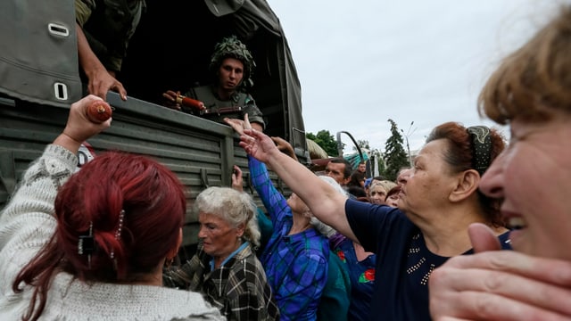 Menschen erhalten Esswaren von einem Militärtransporter